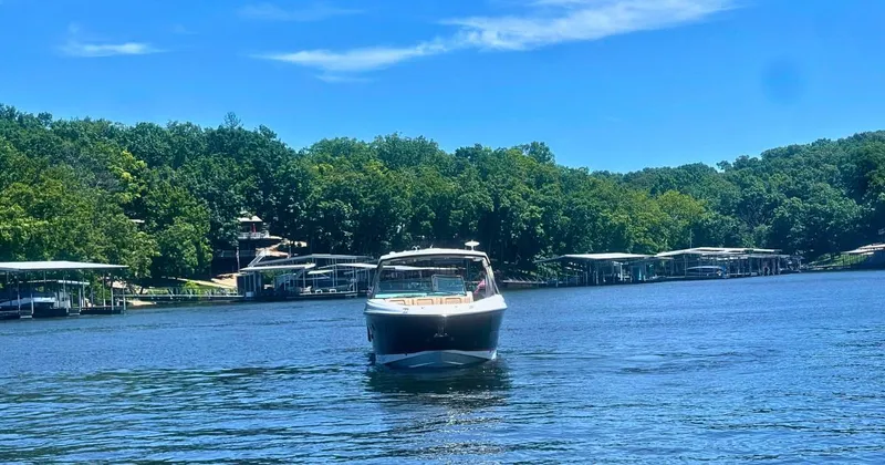 Slide: The Image of 2022 Sea Ray 400 SLX boat cruising on a serene lake with lush green surroundings. - 1