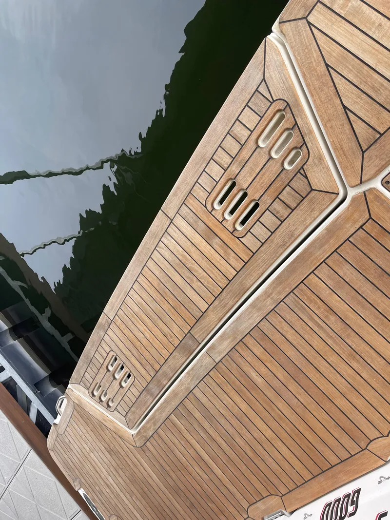 Slide: The Image of 2022 Sea Ray 400 SLX boat deck with teak finish by the water. - 14