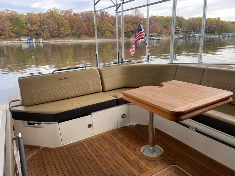 Slide: The Image of Luxurious 2022 Sea Ray 400 SLX boat interior with seating and table, docked by a scenic lake. - 16