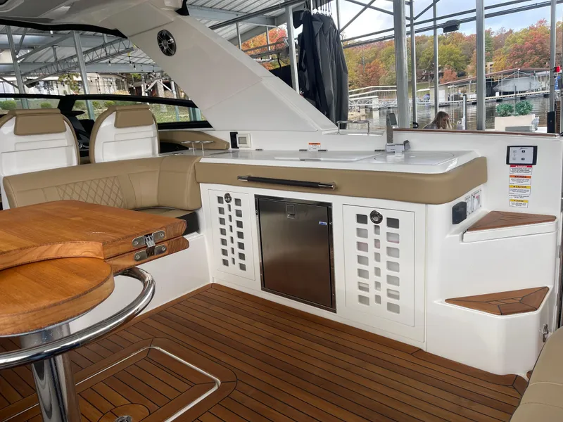 Slide: The Image of 2022 Sea Ray 400 SLX interior with kitchenette and seating, featuring wood accents and modern design. - 17