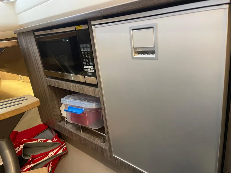 Slide: The Image of 2022 Sea Ray 400 SLX interior with microwave and compact fridge. - 25