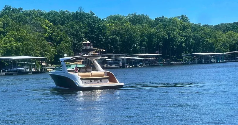Slide: The Image of 2022 Sea Ray 400 SLX cruising on a serene lake with lush green shoreline. - 3