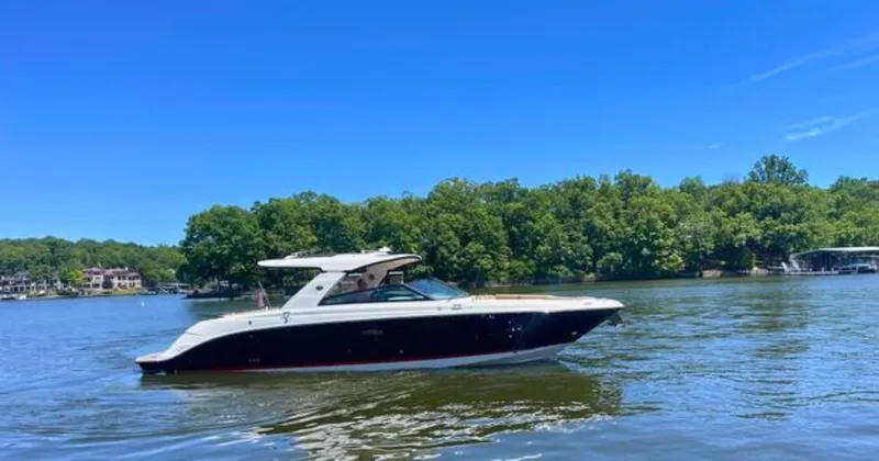 Slide: The Image of 2022 Sea Ray 400 SLX boat cruising on a serene lake with lush green trees. - 4