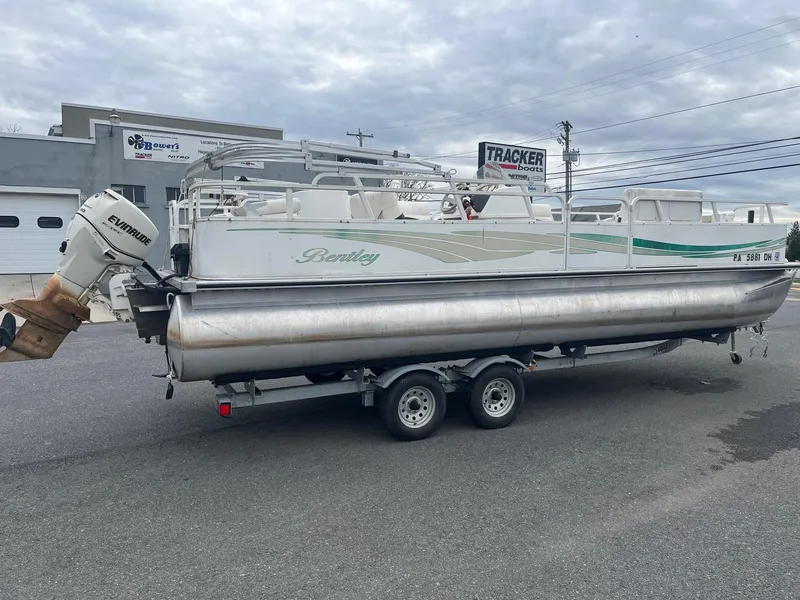 Slide: The Image of 2009 Bentley Pontoons 244 4-point pontoon boat on trailer, parked outdoors. - 1