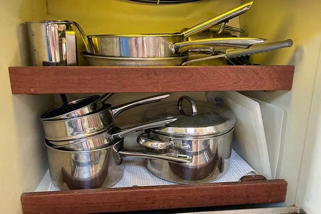 Slide: The Image of Stainless steel cookware neatly stored in a wooden cabinet on a 1981 C&C Landfall 35 sailboat. - 14