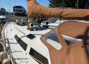 Slide: The Image of 1981 C&C Landfall 35 sailboat with brown canvas cover, docked outdoors. - 2