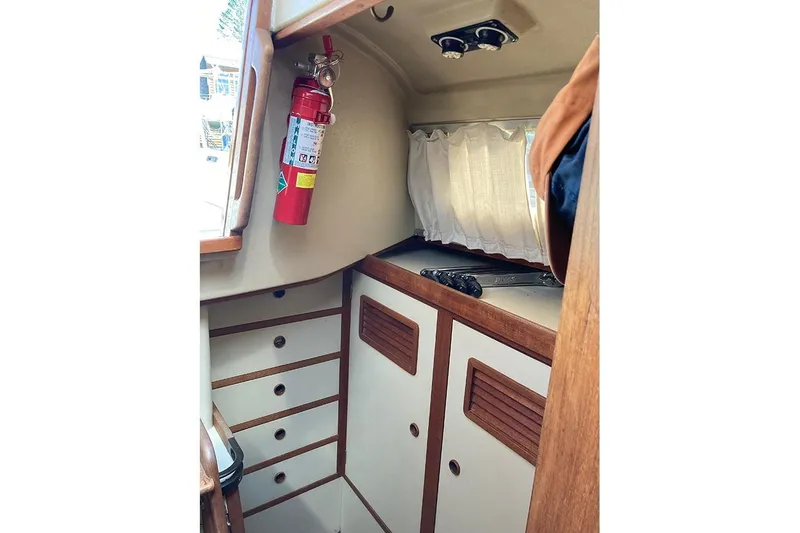 Slide: The Image of 1981 C&C Landfall 35 interior with fire extinguisher, cabinets, and window curtain. - 24