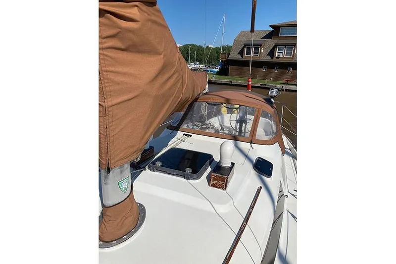 Slide: The Image of 1981 C&C Landfall 35 sailboat deck with brown canvas cover, docked near wooden building. - 34