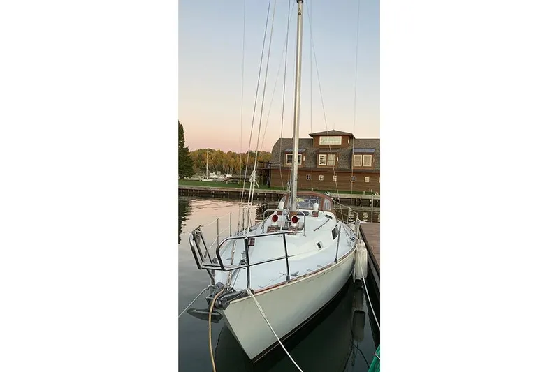 Slide: The Image of 1981 C&C Landfall 35 sailboat docked at sunset near a wooden building. - 42