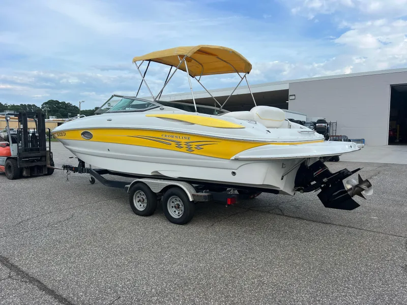 Slide: The Image of 2006 Crownline 240 EX boat with yellow accents on a trailer, parked outdoors. - 4