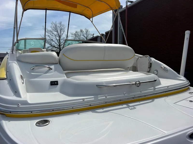 Slide: The Image of 2006 Crownline 240 EX boat with yellow canopy and white seating, docked outdoors. - 5