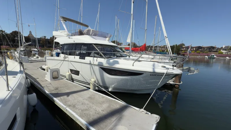 Slide: The Image of 2016 Jeanneau Velasco 37F yacht docked at a marina under clear blue skies. - 2