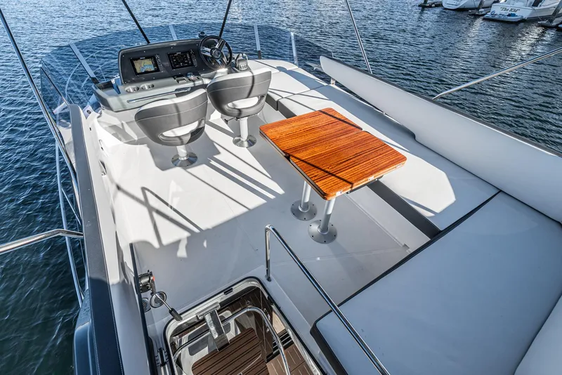 Slide: The Image of 2024 Bavaria R40 yacht deck with helm, seating, and wooden table on water. - 23