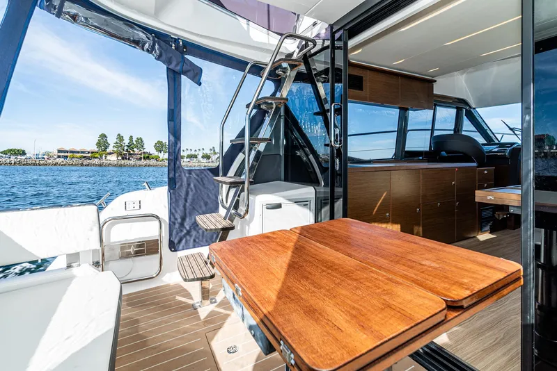 Slide: The Image of 2024 Bavaria R40 yacht interior with wooden table, stairs, and ocean view. - 42