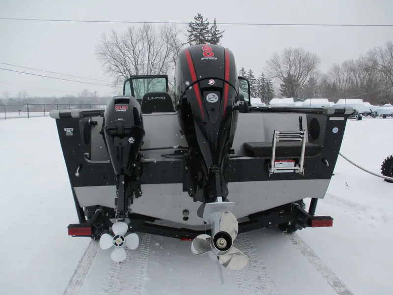Slide: The Image of 2025 Lund 1875 Fisherman Sport boat with dual outboard motors in snowy setting. - 2