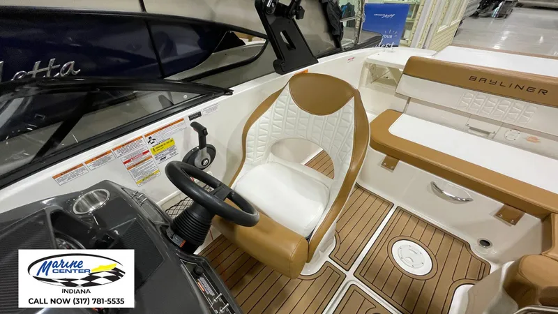 Slide: The Image of 2019 Bayliner VR 5 boat interior with tan and white seating, steering wheel, and wood-style flooring. - 5