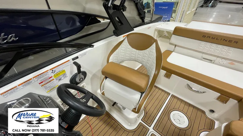 Slide: The Image of 2019 Bayliner VR 5 boat interior with tan seating and steering wheel, Marine Center Indiana logo. - 6