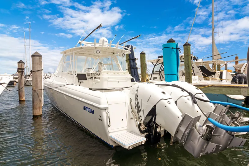 The Image of 2004 Intrepid 377 Walkaround boat docked with triple outboard engines. - 0
