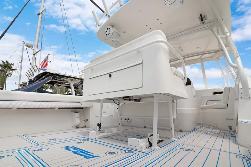 Slide: The Image of 2004 Intrepid 377 Walkaround boat interior with seating and deck, under a clear blue sky. - 11