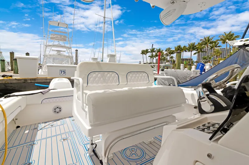 Slide: The Image of 2004 Intrepid 377 Walkaround boat interior with seating, docked under a clear blue sky. - 7