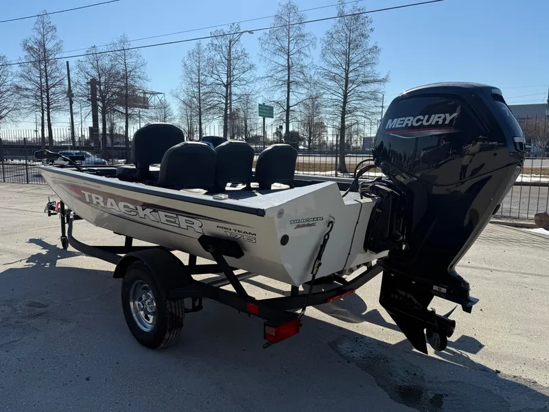 Slide: The Image of 2025 Tracker Pro Team 175 boat with Mercury engine on a trailer, parked outdoors. - 4