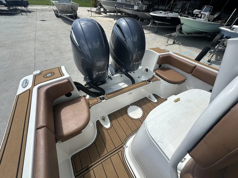 Slide: The Image of 2019 Clearwater 2300 boat interior with dual engines and brown seating. - 3