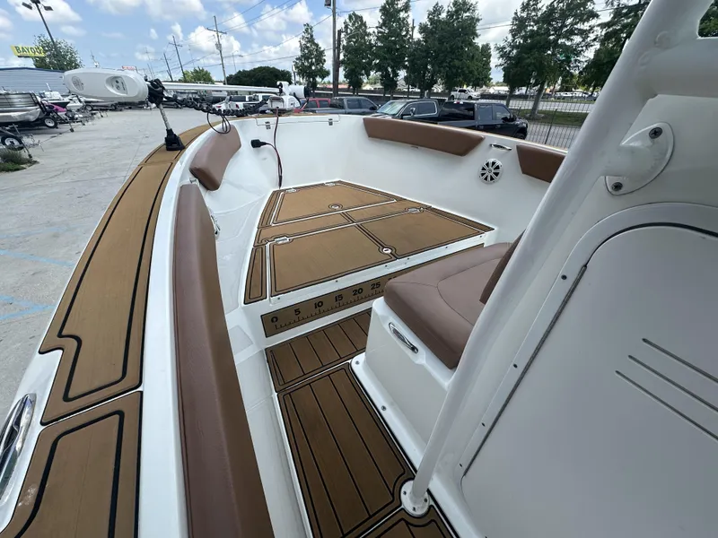 Slide: The Image of 2019 Clearwater 2300 boat interior with brown seating and deck, parked outdoors. - 11