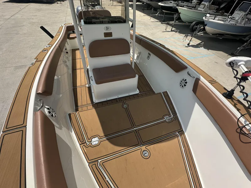 Slide: The Image of 2019 Clearwater 2300 boat interior with brown seating and deck, docked among other boats. - 14