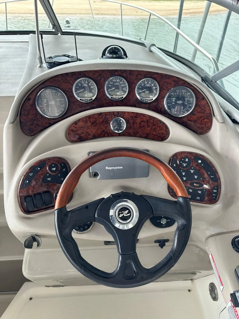 Slide: The Image of Dashboard of 2007 Sea Ray 280 Sundancer boat with wood accents and steering wheel. - 2