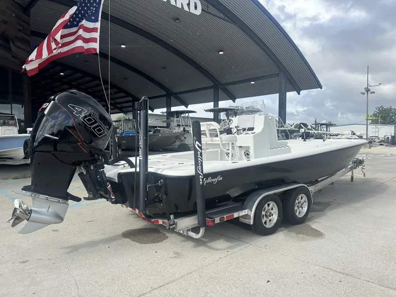 Slide: The Image of 2012 Yellowfin 24 Bay boat on trailer, equipped with Mercury 400 engine, parked outdoors. - 10