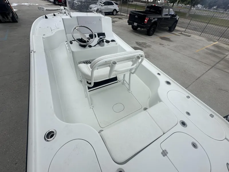 Slide: The Image of 2012 Yellowfin 24 Bay boat interior with steering console and seating, parked near a black truck. - 8