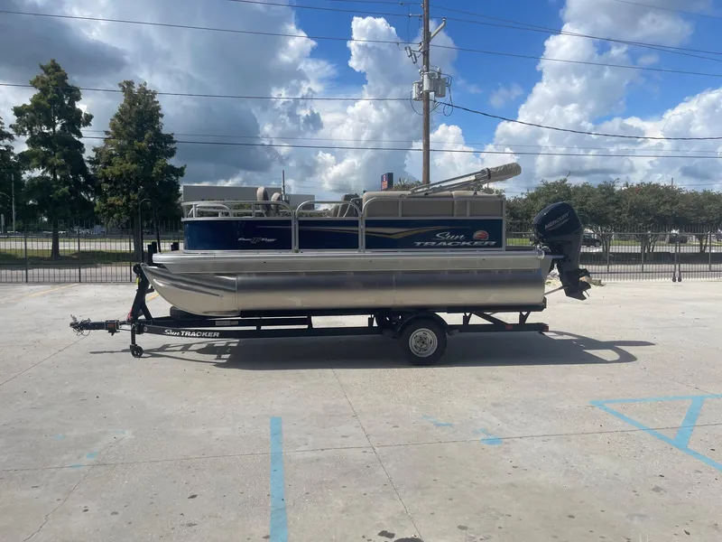 Slide: The Image of 2025 Sun Tracker Bass Buggy 16 XL pontoon boat on trailer, parked outdoors. - 4