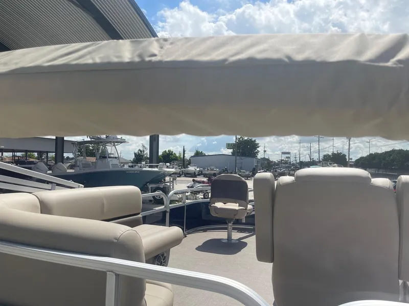 Slide: The Image of 2025 Sun Tracker Bass Buggy 16 XL pontoon boat with beige seating under a sunny sky. - 7