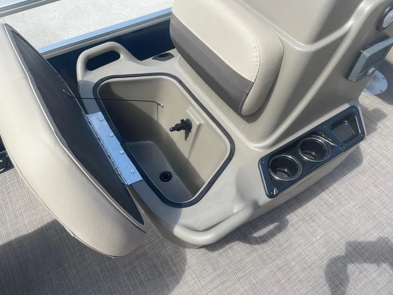 Slide: The Image of 2025 Sun Tracker Bass Buggy 16 XL storage compartment with cup holders and beige seating. - 13