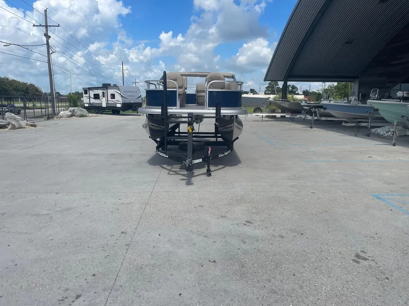 Slide: The Image of 2025 Sun Tracker Bass Buggy 16 XL pontoon boat on trailer in outdoor lot. - 2