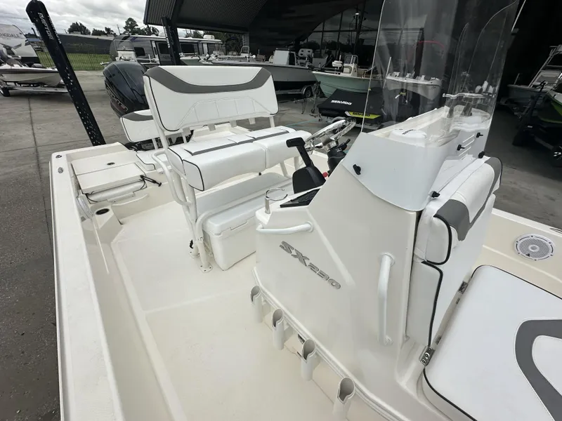Slide: The Image of 2023 Skeeter SX230 boat interior with seating and console, displayed in a showroom. - 26