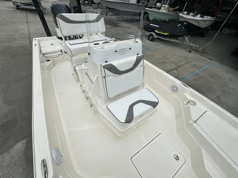 Slide: The Image of 2023 Skeeter SX230 boat interior with white and gray seating, docked in a marina. - 9