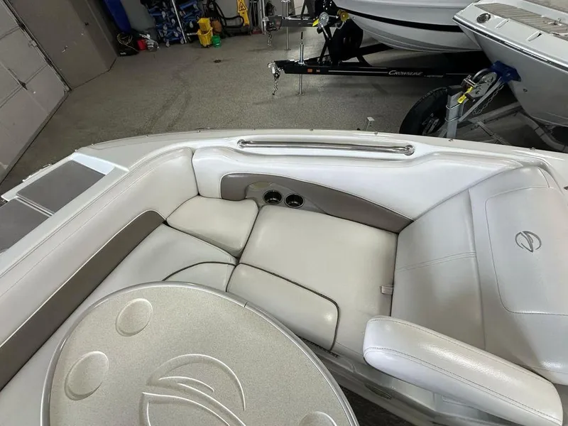 Slide: The Image of 2012 Crownline E1 boat interior with white seating and table in a garage setting. - 5