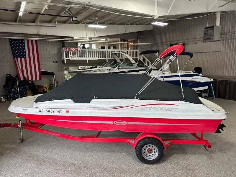 Slide: The Image of Red and white 2011 Starcraft 2000 boat on trailer in indoor showroom. - 15