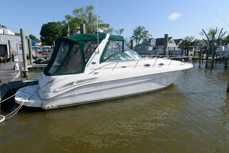 The Image of 2001 Sea Ray 340 Sundancer boat docked in a marina, featuring a green canopy. - 0