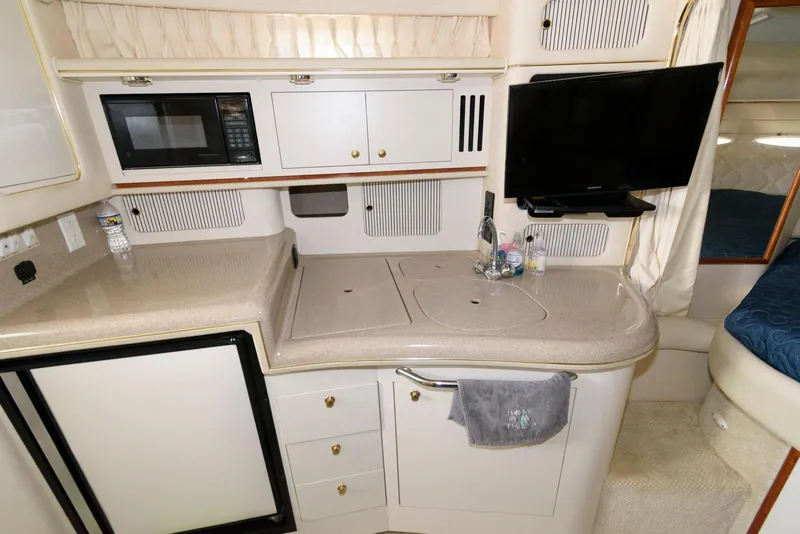 Slide: The Image of 2001 Sea Ray 340 Sundancer interior kitchen with microwave, TV, and compact fridge. - 10