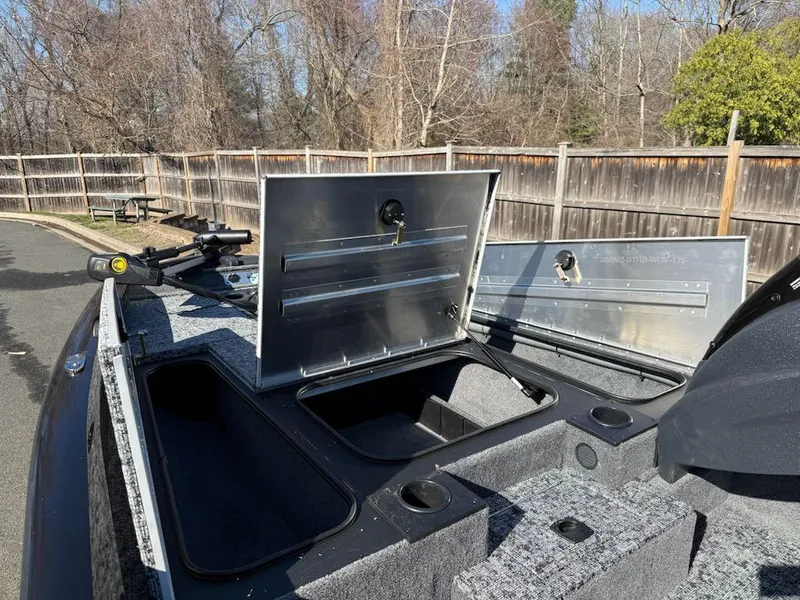 Slide: The Image of 2025 Tracker Pro Team 175 boat with open storage compartments, parked outdoors. - 5