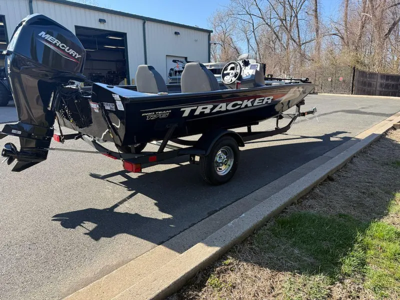 Slide: The Image of 2025 Tracker Pro Team 175 boat with Mercury engine, parked outdoors near a building. - 7