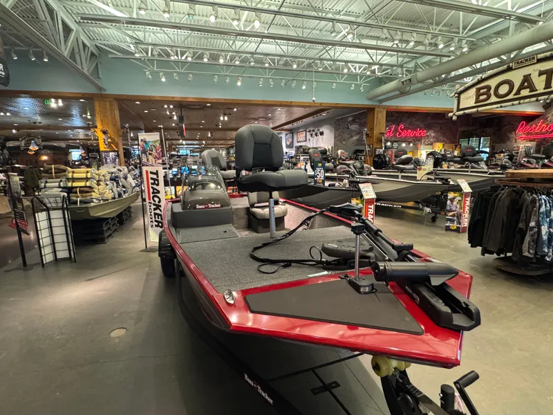 Slide: The Image of 2025 Tracker Bass Tracker Classic XL boat displayed in a showroom with fishing gear. - 3