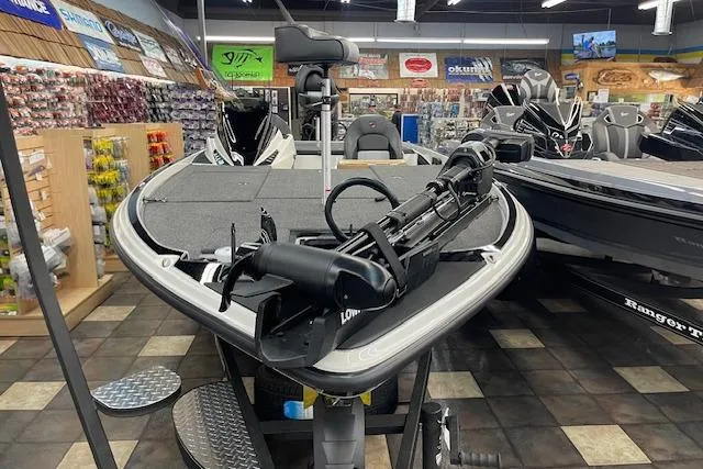 Slide: The Image of 2025 Triton 21XP Patriot boat displayed in a showroom with fishing equipment. - 1