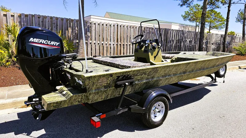 Slide: The Image of 2025 Tracker Grizzly 1860 CC boat with Mercury engine on trailer, parked outdoors. - 2