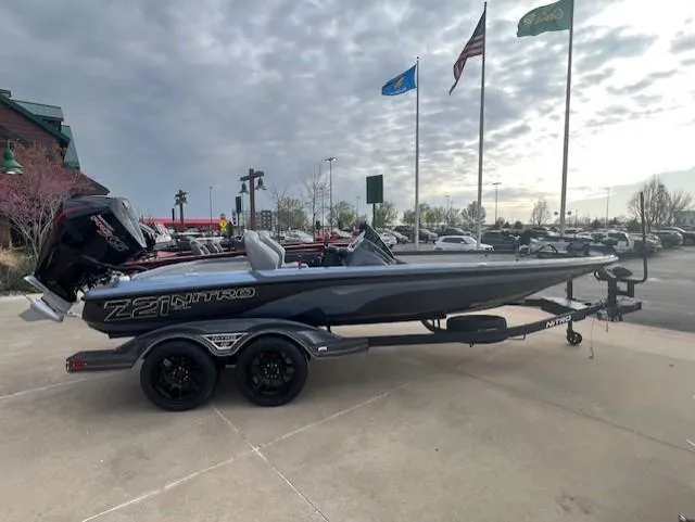 Slide: The Image of 2025 Nitro Z21 XL Pro boat on trailer, parked outdoors with flags in background. - 1