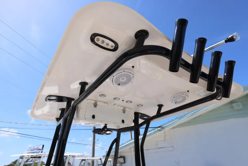 Slide: The Image of 2023 Sea Hunt Ultra 219 T-top with rod holders and speakers, under clear blue sky. - 4