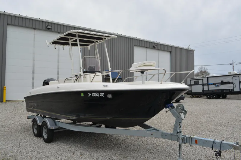 Slide: The Image of 2021 Bayliner Element F21 boat on trailer, parked outside a warehouse. - 1