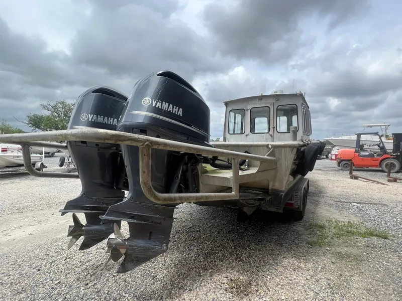 Slide: The Image of Custom Flat 28 Cabin Boat with dual Yamaha engines, parked on gravel under cloudy skies. - 5